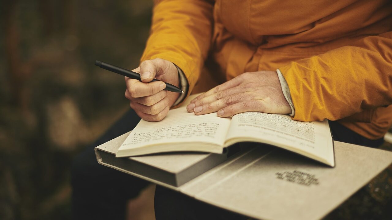 Foto Blog Reflexion: Ausschnitt eines Menschen, der in ein Journal schreibt