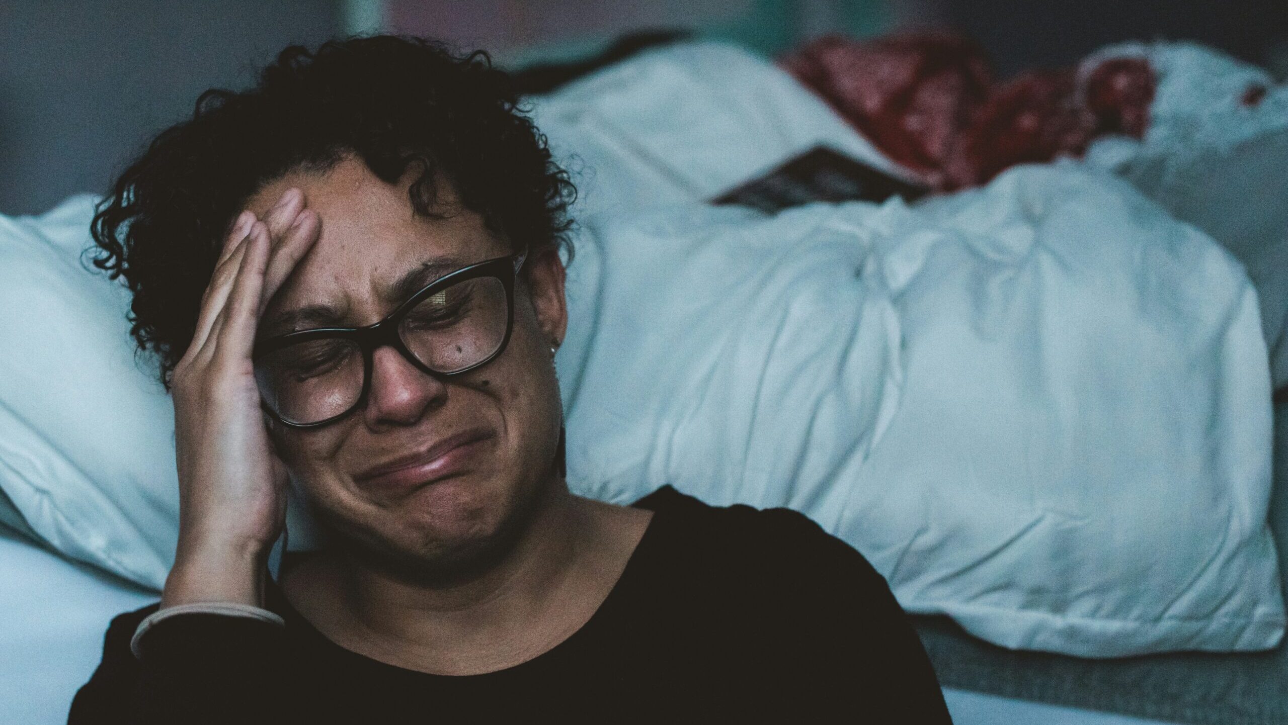 Foto Blog Misstrauen: Eine Person, die vor einem Bett sitzt und weint